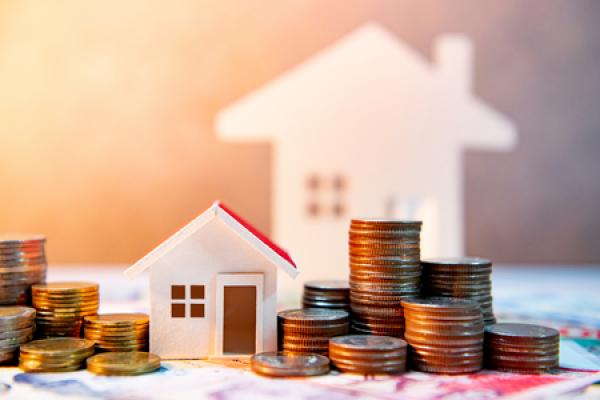 A pile of coins next to a miniature home